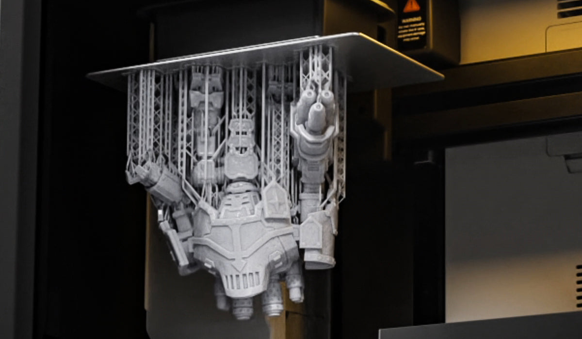 UniFormation promotional photo of a supported resin robot model hanging from the S10 build plate.