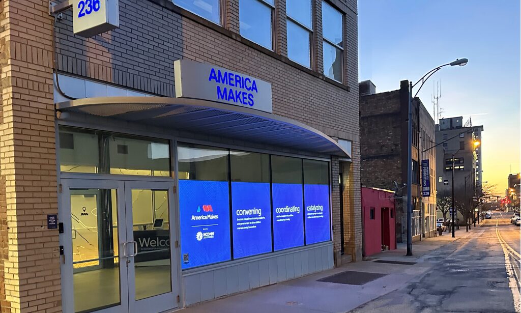 Exterior of the America Makes facility with blue signage and window graphics.