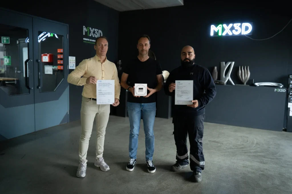 MX3D announcement photograph of three people displaying DNV certification documents and a plaque.